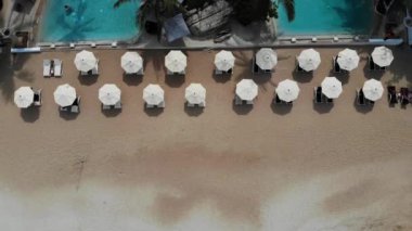 Plajda şezlong. Temiz kum ile ıssız plajda şemsiye ile birçok eşleştirilmiş şezlong havadan görünümü.