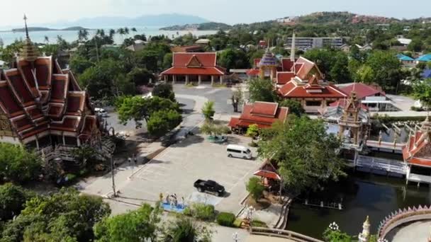 Buddhistischer Tempel in der Nähe des Sees. Drone Drone Ansicht von Dächern und Statuen von wunderbaren buddhistischen Tempel in der Nähe des Sees an einem sonnigen Tag auf ko samui. wat plai laem mit lächelndem Buddha und guan yin — Stockvideo