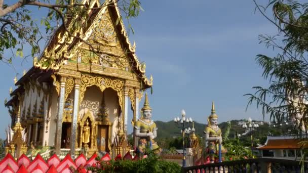 Patung berwarna-warni dekat kuil Asia. Dua patung berwarna cerah yang terletak di dekat kuil Buddha ornamental pada hari yang cerah di negara oriental. Banteng penjaga raksasa mitos di Wat Plai Laem. Koh Samui . — Stok Video