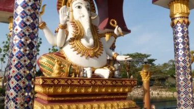 Hindu tapınağındaki Ganesha Heykeli. Asya ülkesinde güneşli bir günde geleneksel Hindu tapınağının bahçesinde bulunan altın süslemeleri ve fil kafası ile Ganapati Heykeli. Wat Plai Laem. Koh Samui.