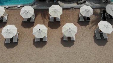 Plajda şezlong. Temiz kum ile ıssız plajda şemsiye ile birçok eşleştirilmiş şezlong havadan görünümü.