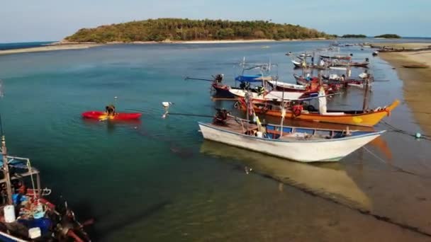 Halászhajók a part közelében. Különböző színes halászhajók úszó part közelében a tengervíz trópusi országban. Drone felülnézet óceán tengerpart táj horgonyzott fa hagyományos halászhajók — Stock videók