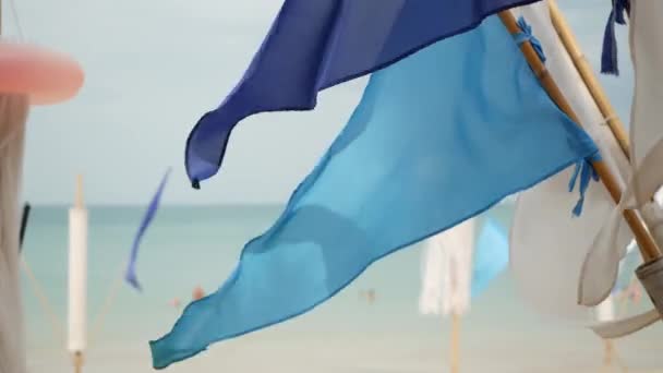 Banderas azules ondeando en el viento. Pequeñas banderas azules triangulares ondeando en el viento en tiempo nublado en la playa tropical — Vídeos de Stock