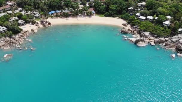 Small houses on tropical island. Tiny cozy bungalows located on shore of Koh Samui Island near calm sea on sunny day in Thailand. Volcanic rocks and cliffs drone top view. — Stock Video
