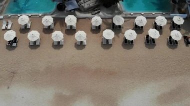Plajda şezlong. Temiz kum ile ıssız plajda şemsiye ile birçok eşleştirilmiş şezlong havadan görünümü.