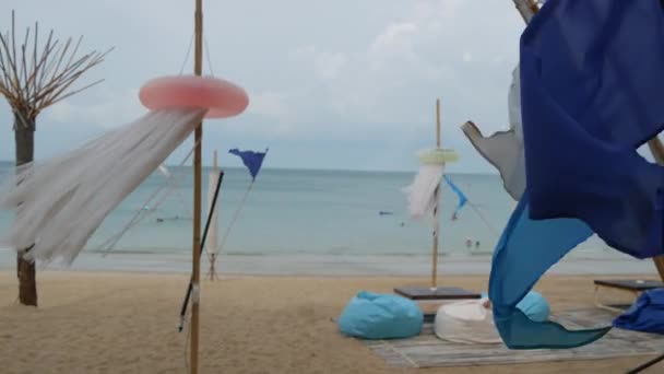 Blue flags waving in wind. Small triangular blue flags fluttering in wind in cloudy weather on tropical beach — Stock Video