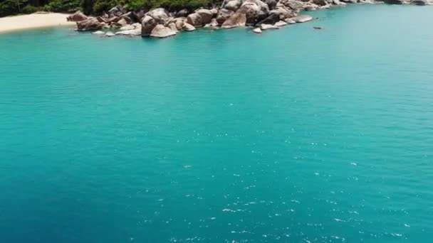 Small houses on tropical island. Tiny cozy bungalows located on shore of Koh Samui Island near calm sea on sunny day in Thailand. Volcanic rocks and cliffs drone top view. — Stock Video