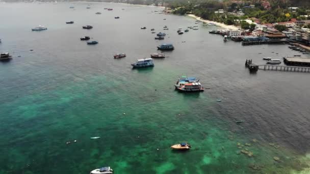 Lodě v klidném moři v přístavu. Dron pohled na rybolov a potápěčské lodě plovoucí na klidném povrchu modrého moře v přístavu tropického exotického ráje Koh Tao Island za slunečného dne v Thajsku — Stock video