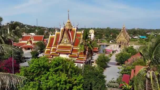 Templo budista perto do lago. Drone vista superior de telhados e estátuas de templo budista maravilhoso localizado perto do lago no dia ensolarado em Ko Samui. Wat Plai Laem com Buda Sorrindo e Guan Yin — Vídeo de Stock