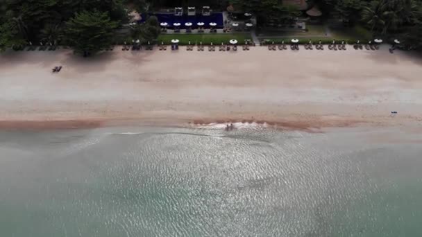 Лежаки на пляже. Вид с воздуха на многие парные шезлонги с зонтиком на пустынном пляже с чистым песком . — стоковое видео