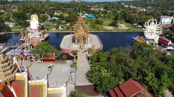 Buddhista templom közelében tó. Drone felülnézetben tetők és szobrok a csodálatos buddhista templom közelében található tó napsütéses napon a Ko Samui. Wat Plai Laem a mosolygó Buddha és Guan Yin — Stock videók