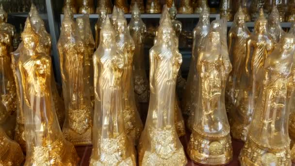 Buddha-Statuetten im religiösen Geschäft zum Verkauf. viele goldene Buddha-Statuetten, die in einem religiösen Geschäft in der Nähe eines Tempels in einem asiatischen Land aufgestellt wurden — Stockvideo