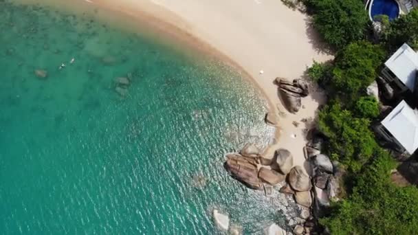 Piccole case sull'isola tropicale. Piccoli bungalow accoglienti situati sulla riva dell'isola di Koh Samui vicino al mare calmo nella giornata di sole in Thailandia. Rocce vulcaniche e scogliere drone vista dall'alto. — Video Stock