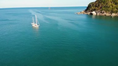 Tropikal kıyıya yakın bir tekne. Tropik volkanik adanın kıyıları yakınlarındaki sakin deniz suyunda seyreden modern yatın insansız hava aracı görüntüsü. Egzotik Cennet Koh Samui, Silver Beach.