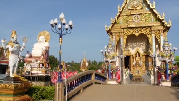 Barevné sochy poblíž asijského chrámu. Okrasný buddhistický chrám za slunečného dne v orientální zemi. Socha Hotei mimo buddhistický chrám. Tradiční socha šťastné Hotei v Wat Plai Laem. Koh Samui. — Stock video