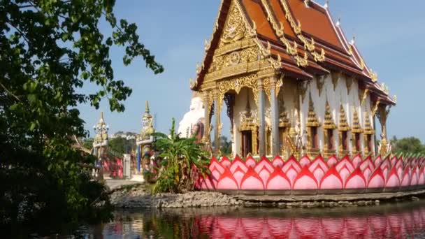 Farbenfrohe Statuen in der Nähe asiatischer Tempel. zwei leuchtend bunte Statuen in der Nähe buddhistischer Ornamente an sonnigen Tagen im orientalischen Land. mythische riesige Wächteryak am wat plai laem. koh samui. — Stockvideo