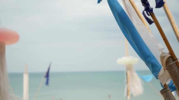 Modré vlajky vlající ve větru. Malé trojúhelníkové modré vlajky vlající ve větru v oblačném počasí na tropické pláži — Stock video