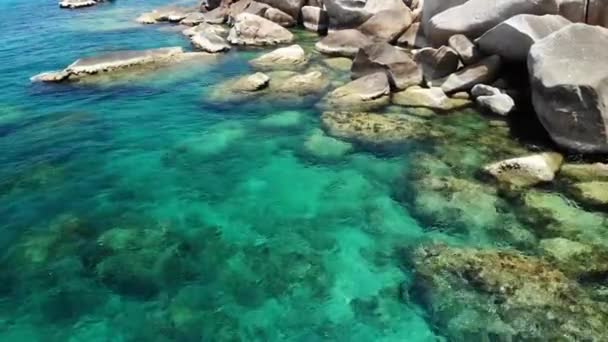 石の近くの穏やかな海の水。タイの晴れた日にタオタオ島でシュノーケリングするのに最適な場所にある穏やかな青い海の水と灰色の岩。天然の背景色. — ストック動画