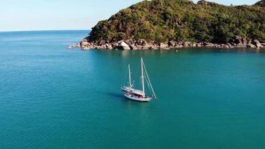 Tropikal kıyıya yakın bir tekne. Tropik volkanik adanın kıyıları yakınlarındaki sakin deniz suyunda seyreden modern yatın insansız hava aracı görüntüsü. Egzotik Cennet Koh Samui, Silver Beach.