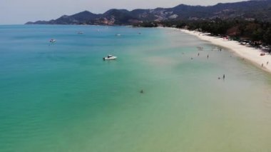 Tatil köyündeki mavi denizde motorlu yatlar. Güneşli bir günde tropikal bir tatil köyünde plaj yakınlarında sakin bir deniz yüzeyinde yüzen modern motorlu yatlar. Koh Samui cenneti egzotik Chaweng plaj drone manzarası.