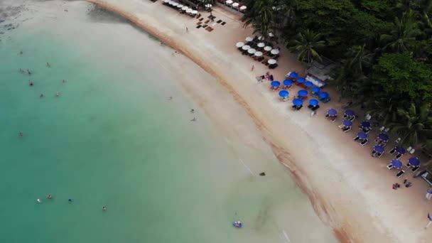 海滩上的日光浴床。在荒凉的海滩上,许多配对的太阳椅与伞与干净的沙滩的鸟瞰图. — 图库视频影像