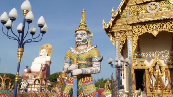 Kleurrijke standbeelden in de buurt van de Aziatische tempel. Sier boeddhistische tempel op zonnige dag in Oosterse land. Hotei standbeeld buiten boeddhistische tempel. Traditionele Happy Hotei beeldhouwkunst in wat Plai Laem. Koh Samui. — Stockvideo