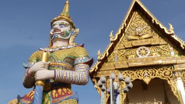 Kleurrijke standbeelden in de buurt van de Aziatische tempel. Twee heldere veelkleurige standbeelden gelegen in de buurt van de decoratieve boeddhistische tempel op zonnige dag in Oosterse land. Mythische reus Guardian yak in wat Plai Laem. Koh Samui. — Stockvideo