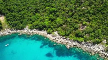 Tropik volkanik adanın yakınındaki sakin deniz. Güneşli Tayland 'da, güneşli bir günde, taşlı kıyılar yakınlarındaki huzurlu mavi denizin insansız hava aracı manzarası ve volkanik Koh Tao Adası' nın yeşil ormanı..