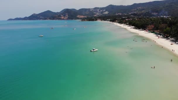 Yates de motor en el mar azul en el complejo. Yates a motor modernos flotando en la superficie tranquila del mar azul cerca de la playa en el día soleado en el complejo tropical. Koh Samui paraíso exótico Chaweng playa drone vista. — Vídeo de stock