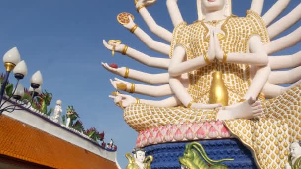 Budizm tapınağının bahçesindeki Guanyin Heykeli. Guan Yin heykeli birçok silah doğu ülkede bulutsuz mavi gökyüzüne karşı geleneksel Budist tapınağının bahçesinde bulunan. Wat Plai Laem. Koh Samui. — Stok video