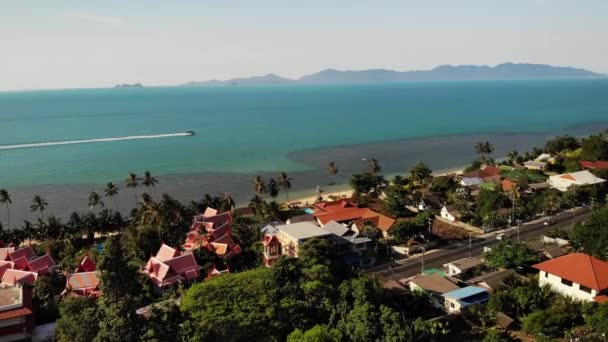 Estrada e casas na praia. Vista drone da estrada principal e casas costeiras na Ilha Ko Samui no dia ensolarado na Tailândia. Bang Po exótica praia tropical. — Vídeo de Stock