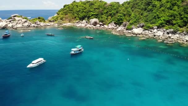 Barcos turísticos en bahía tropical. Drone vista de los barcos turísticos con buceadores y buceadores flotando en el agua de mar tranquila en la bahía de Hin Wong de la isla volcánica tropical de Koh Tao en Tailandia. — Vídeo de stock