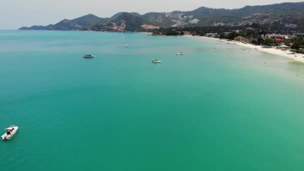 Motoryachten im blauen Meer vor Ort. Moderne Motoryachten, die an einem sonnigen Tag im tropischen Badeort auf einer ruhigen Oberfläche des blauen Meeres in Strandnähe schwimmen. Koh Samui Paradies exotische Chaweng Strand Drohne Ansicht. — Stockvideo