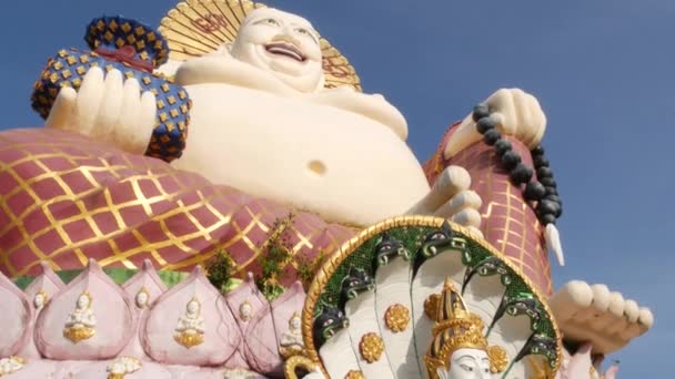 Hotei Staty utanför buddhistiska templet. Traditionella Happy hotei skulptur ligger på gården av buddhismen helgedom mot molnfri blå himmel i Asien land. Wat Plai Laem. Koh Samui. — Stockvideo