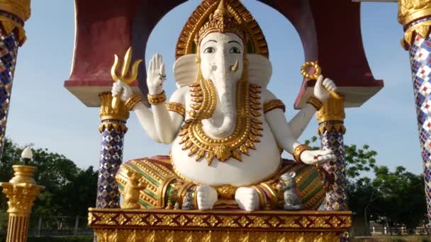 Hindu tapınağındaki Ganesha Heykeli. Asya ülkesinde güneşli bir günde geleneksel Hindu tapınağının bahçesinde bulunan altın süslemeleri ve fil kafası ile Ganapati Heykeli. Wat Plai Laem. Koh Samui. — Stok video