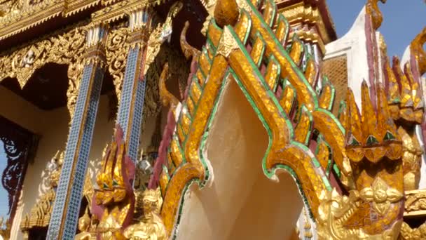 Ozdobna dach orientalnej świątyni. Złoty ozdobny dach tradycyjnej azjatyckiej świątyni przed bezchmurnym błękitnym niebem w słoneczny dzień. Wat Plai Laem. Koh Samui. — Wideo stockowe