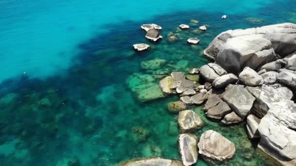 Lugnt havsvatten nära stenar. Lugnt blått havsvatten och gråstenar på perfekt plats för snorkling på Koh Tao Island på solig dag i Thailand. Naturlig bakgrund struktur. — Stockvideo