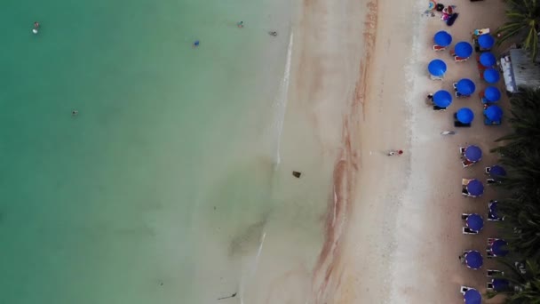 ビーチのサンベッド。きれいな砂と砂漠のビーチに傘を持つ多くのペアのサンラウンジャーの航空写真. — ストック動画