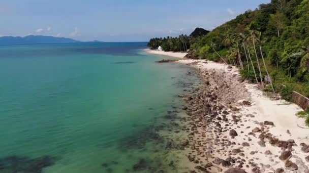 Zielona dżungla i kamienista plaża w pobliżu morza. Tropikalny las deszczowy i skały w pobliżu spokojnego błękitnego morza na białym, piaszczystym brzegu rajskiej wyspy Koh Samui, Tajlandia. Wymarzony widok na plażę. Relaks i koncepcja wakacje. — Wideo stockowe