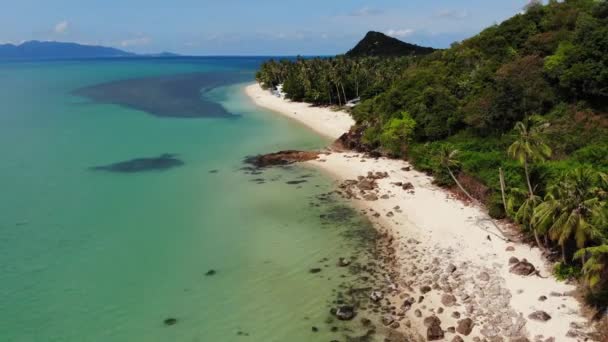 海の近くの緑のジャングルと石のビーチ。タイのサムイ島のパラダイス島の白い砂浜の海岸にある穏やかな青い海の近くの熱帯雨林と岩。夢のビーチドローンビュー。リラックスして休暇のコンセプト. — ストック動画