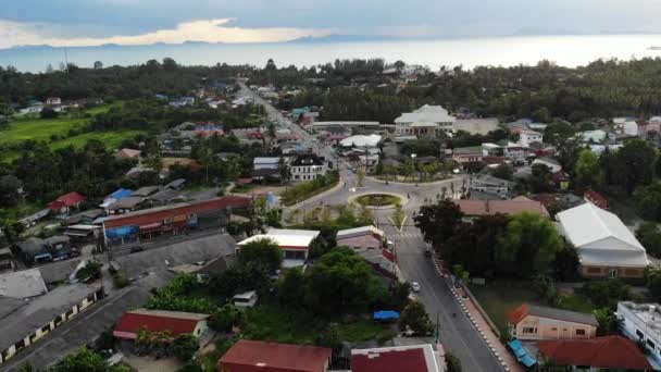 Cars riding on roundabout in small town near jungle. Vehicles riding on circular intersection of main road in middle of small town against the sea on Koh Samui Island Thailand. Drone view — Stock Video