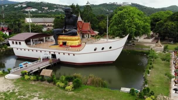 Zwarte monnik standbeeld op schip in vijver. Enorme zwarte monnik sculptuur gelegen in het midden van het schip gevormde structuur in kleine vijver op Koh Samui eiland in Thailand. Drone-weergave. — Stockvideo