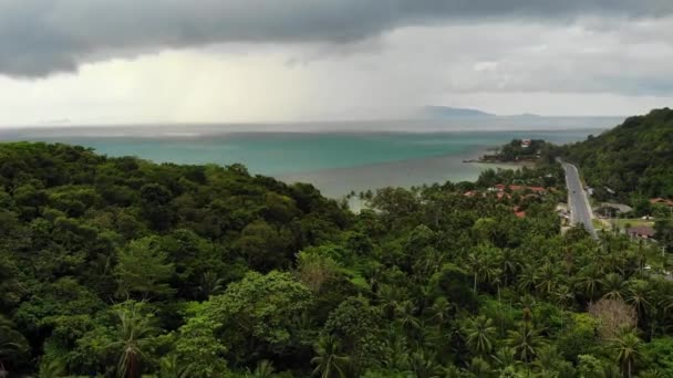 Overskyet over tropiske øyer. Grå skyer, grønne håndflater på Koh Samui under våtsesongen i Thailand. Utsikt over dronen. Flyr over vill regnskog og jungel nær paradis. Storm i Asia – stockvideo
