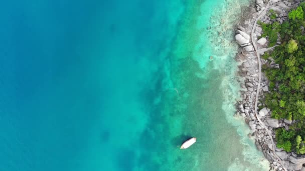 小さな熱帯火山島の近くに穏やかなカラフルな紺碧のターコイズブルーの海コタオ、ユニークな小さな楽園ナン元。タイ王国の晴れた日には、石造りの海岸と緑のジャングルの近くの平和的な水のドローンビュー. — ストック動画