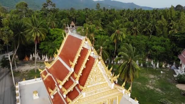 Κλασικός βουδιστικός ναός ανάμεσα στο δάσος. Από πάνω δείτε drone βουδιστικό μοναστήρι μεταξύ πράσινα δέντρα κοντά στο λόφο στην Ταϊλάνδη. Κο Σαμούι. έννοια του τουρισμού, διαλογισμό και ανατολίτικη ζωή. Ασιατικό χωριό — Αρχείο Βίντεο