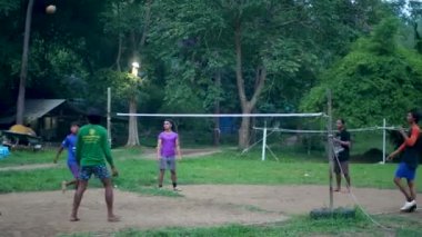 ANG THAILAND - 9 HAZİRAN 2019 Taylandlı gençler parkta sepak oynuyorlar. Yerel yerleşim bölgesindeki yeşil ağaçlara karşı voleybol oynayan bir grup adam. Geleneksel ulusal spor oyunu