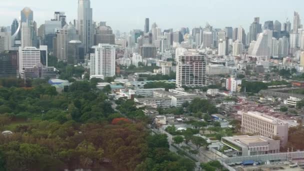 大都市の緑の公園。道路近くのルンピニ公園の緑の木のドローンビューとバンコク、タイの通りに高層ビル — ストック動画