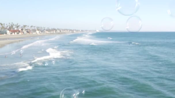 Burbujas de jabón en el muelle en California, fondo borroso en bucle sin costuras durante el verano. Metáfora romántica creativa, concepto de ensueño, felicidad y magia. Símbolo abstracto de infancia, fantasía, libertad — Vídeos de Stock