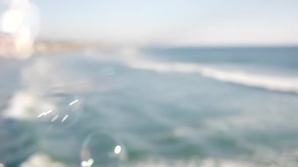 Burbujas de jabón en el muelle en California, fondo borroso en bucle sin costuras durante el verano. Metáfora romántica creativa, concepto de ensueño, felicidad y magia. Símbolo abstracto de infancia, fantasía, libertad — Vídeo de stock