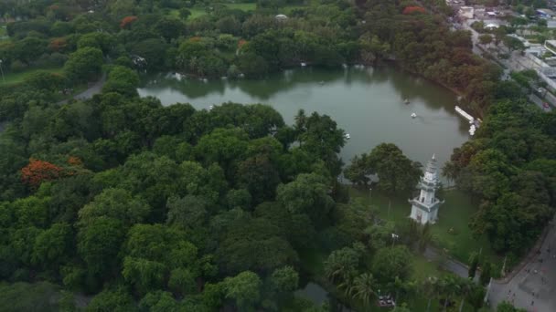 大都市の緑の公園。道路近くのルンピニ公園の緑の木のドローンビューとバンコク、タイの通りに高層ビル — ストック動画